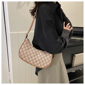 Model wearing a retro monogram crescent hobo bag in cream canvas and brown leather trim
