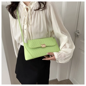 Detail of lime green quilted handbag with golden buckle and sleek leather shoulder strap