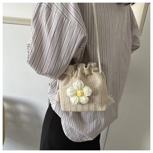 Detail of hand-woven beige bucket bag with large 3D white sunflower and drawstring