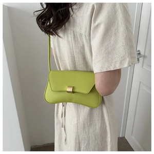Lime green baguette bag with curved bottom and golden buckle shown on shoulder