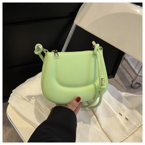 Detail of neon green mini saddle bag with knotted strap and gold hardware accents