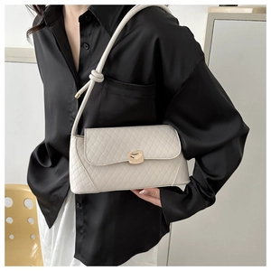 Detail of cream baguette bag with quilted diamond pattern and gold magnetic buckle closure
