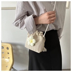 Detail of hand-woven cream bucket bag featuring a 3D knit flower and drawstring closure