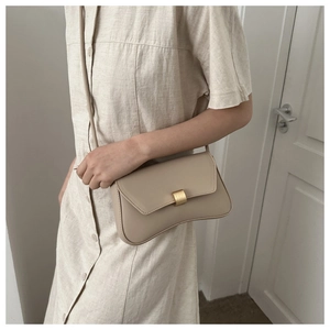 Detail of a beige vintage leather baguette bag with curved hourglass base and gold buckle