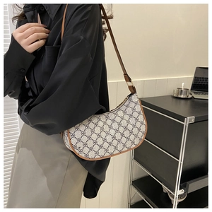 Detail of a beige crescent bag with geometric floral patterns and brown leather strap