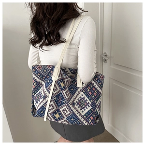 Close-up of geometric ethnic pattern weaving and white faux leather strap on large tote bag