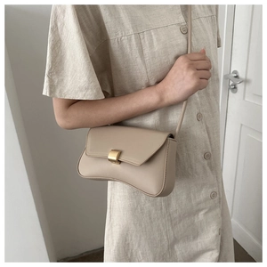 Side view of a beige baguette shoulder bag with gold square buckle worn by a model