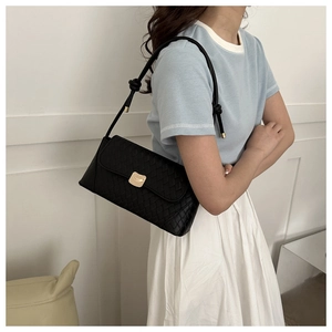 Detail of a black woven leather shoulder bag with a gold curved metal buckle on a model