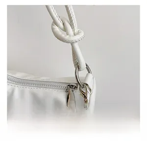 Detailed shot of silver hardware and pearl chain on a white leather shoulder bag
