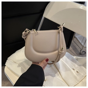 Detail of beige saddle bag with U-shaped quilting and knotted thin shoulder strap