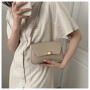 Close-up of beige leather shoulder bag featuring a matte gold buckle and knotted strap