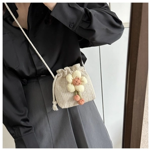 Detail of mini straw woven bucket bag with floral decor and drawstring closure