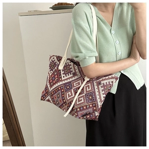 Close-up of geometric woven tote bag with colorful ethnic patterns and cream leather straps
