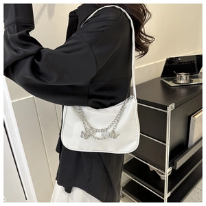 Close-up of a white nylon underarm bag featuring silver chunky chains and butterfly charms