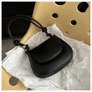 Detail view of black matte leather shoulder bag with cloud-like embossed flap and knotted strap
