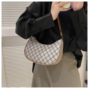 Close-up of retro crescent bag with clover pattern and brown leather trim on a model