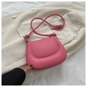 Detail of pink saddle bag with knot strap on beige blazer, showing soft texture