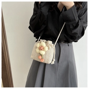 Detailed texture of beige woven bucket bag with yellow floral charm and white rope strap