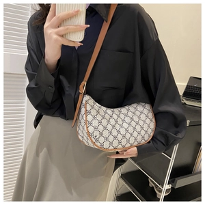 Adjustable brown leather strap detail on a monogram printed crescent hobo crossbody bag