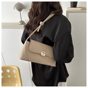 Detail of khaki quilted shoulder bag featuring gold clasp and knotted strap on model