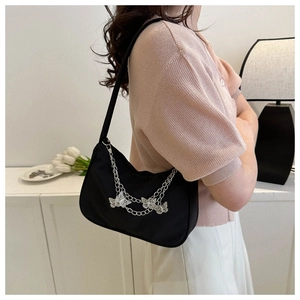Detail of black nylon underarm bag with decorative silver butterfly metal chain strap