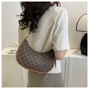 Close-up of vintage brown crescent bag with clover pattern worn by a model