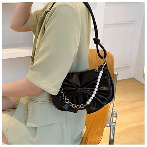 Detail of black bow shoulder bag featuring a white pearl chain and PU leather texture