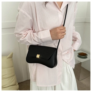 Detail of a black leather bag featuring a curved base and a golden rectangular metal clasp