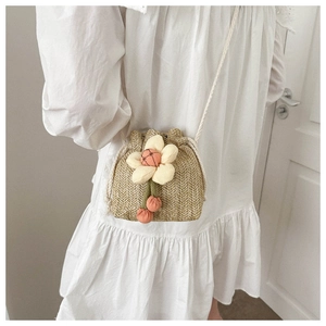 Detail view of mini straw bucket bag featuring 3D sunflower decor and woven texture