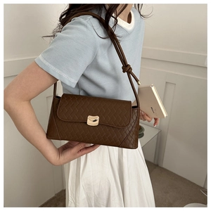 Detail of dark brown woven texture shoulder bag with golden buckle and knotted strap