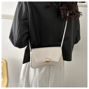Chic beige baguette bag with gold metal buckle shown styled with a black leather jacket