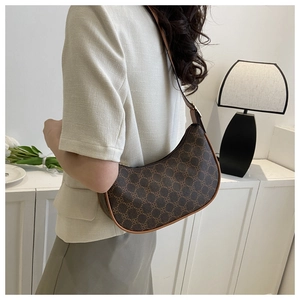 Close-up of vintage brown monogram crescent bag with leather trim on model's shoulder