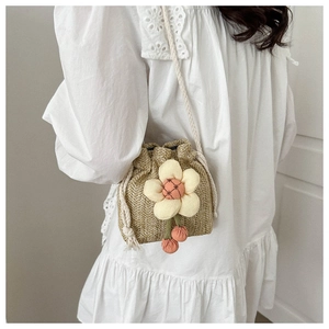 Detail of mini straw bucket bag with floral charm and woven texture for summer