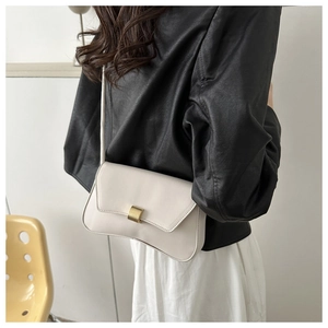 Close-up of matte white baguette bag featuring a rectangle gold buckle on leather flap