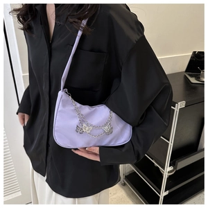 Detail of lavender crescent shoulder bag featuring elegant butterfly charms and silver chains