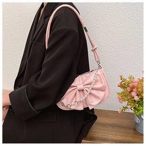 Close-up of pink shoulder bag featuring a large bow and pearl chain with metal petals