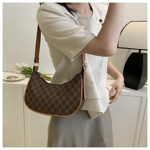 Close-up of vintage brown crescent bag with pattern and adjustable shoulder strap worn by model