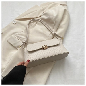 Macro view of beige quilted handbag with golden lock and knotted strap detail