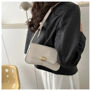 Side view of cream baguette shoulder bag with gold buckle and knotted strap detail