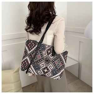 Close-up of bohemian geometric woven canvas tote bag worn on shoulder by a model