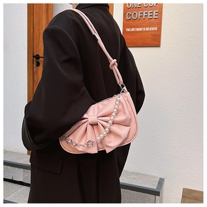 Close-up of pink bow hobo bag featuring elegant pearl chain and soft pleated texture