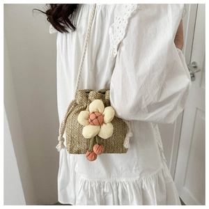 Detailed shot of mini straw bucket bag featuring a large 3D floral accent and woven rope strap