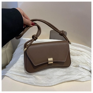 Detail of coffee brown crossbody bag with gold buckle and unique knot shoulder strap