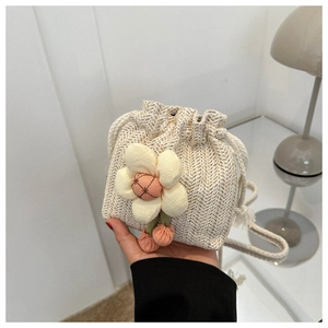 Close-up of mini woven bucket bag with 3D plush flower and drawstring closure