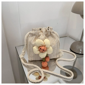 Detail of hand-woven bucket bag with large yellow 3D floral accent and drawstring top