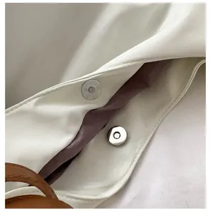 Detail shot of the handbag featuring a magnetic snap closure and soft pink inner lining
