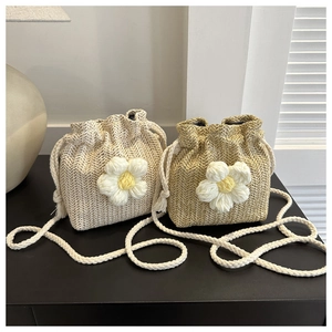 Close-up of hand-woven straw bucket bags with large daisy motifs and cotton drawstring straps