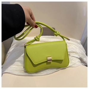 Detail of light green faux leather baguette bag with gold buckle and knotted shoulder strap