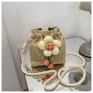 Detail of a mini straw bucket bag with a plush white flower and braided rope strap