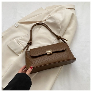 Detail of brown quilted shoulder bag with gold hardware on beige aesthetic background